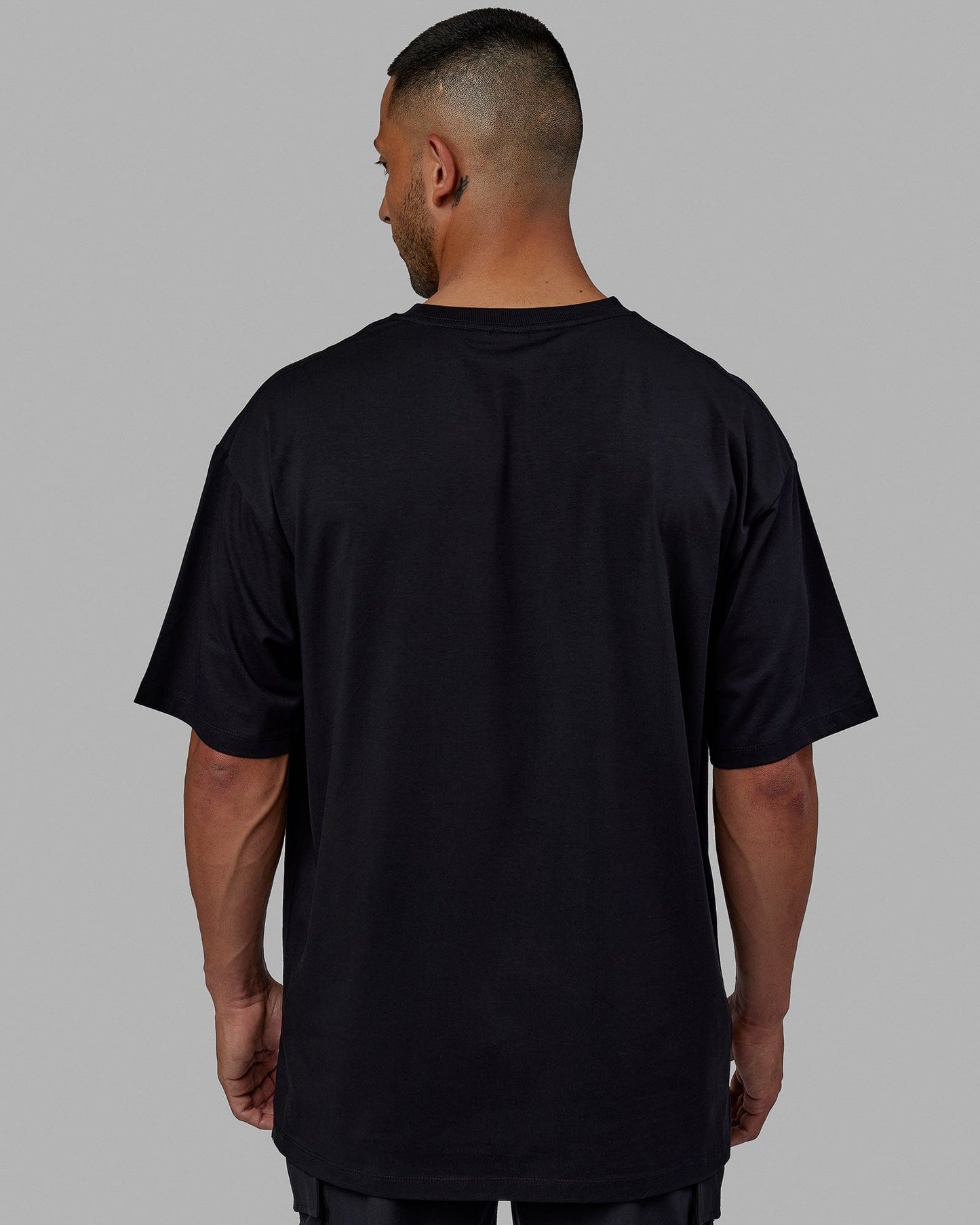 Man wearing Unisex PimaFLX Tee Oversize - Black