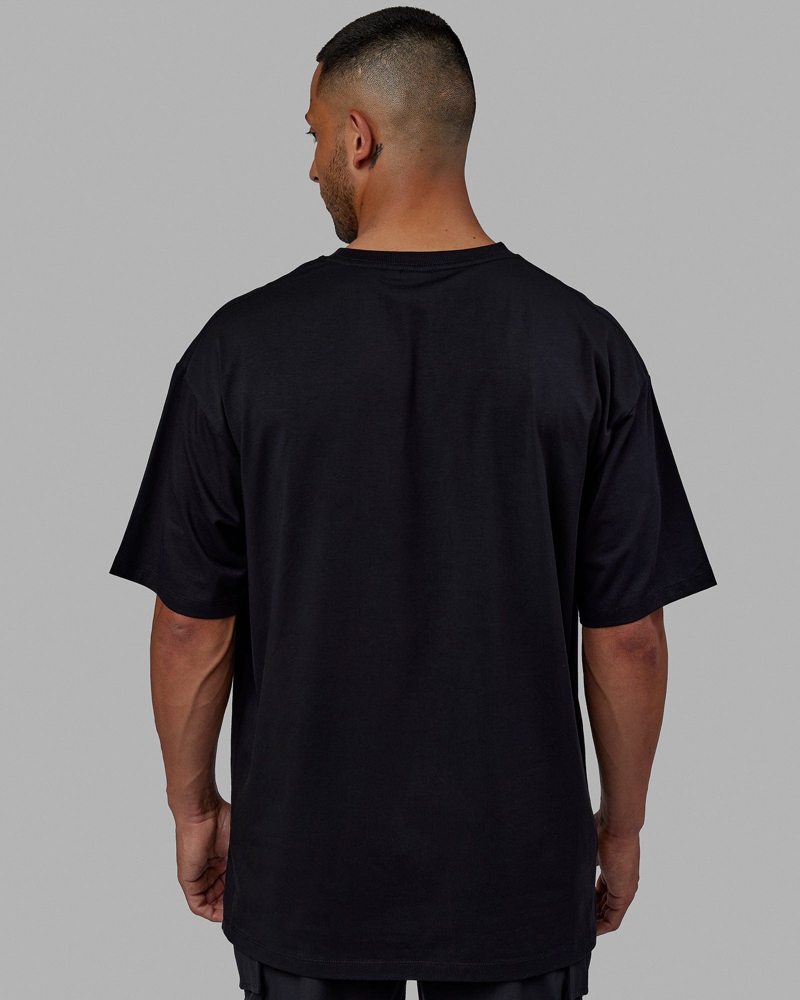 Man wearing Unisex PimaFLX Tee Oversize - Black