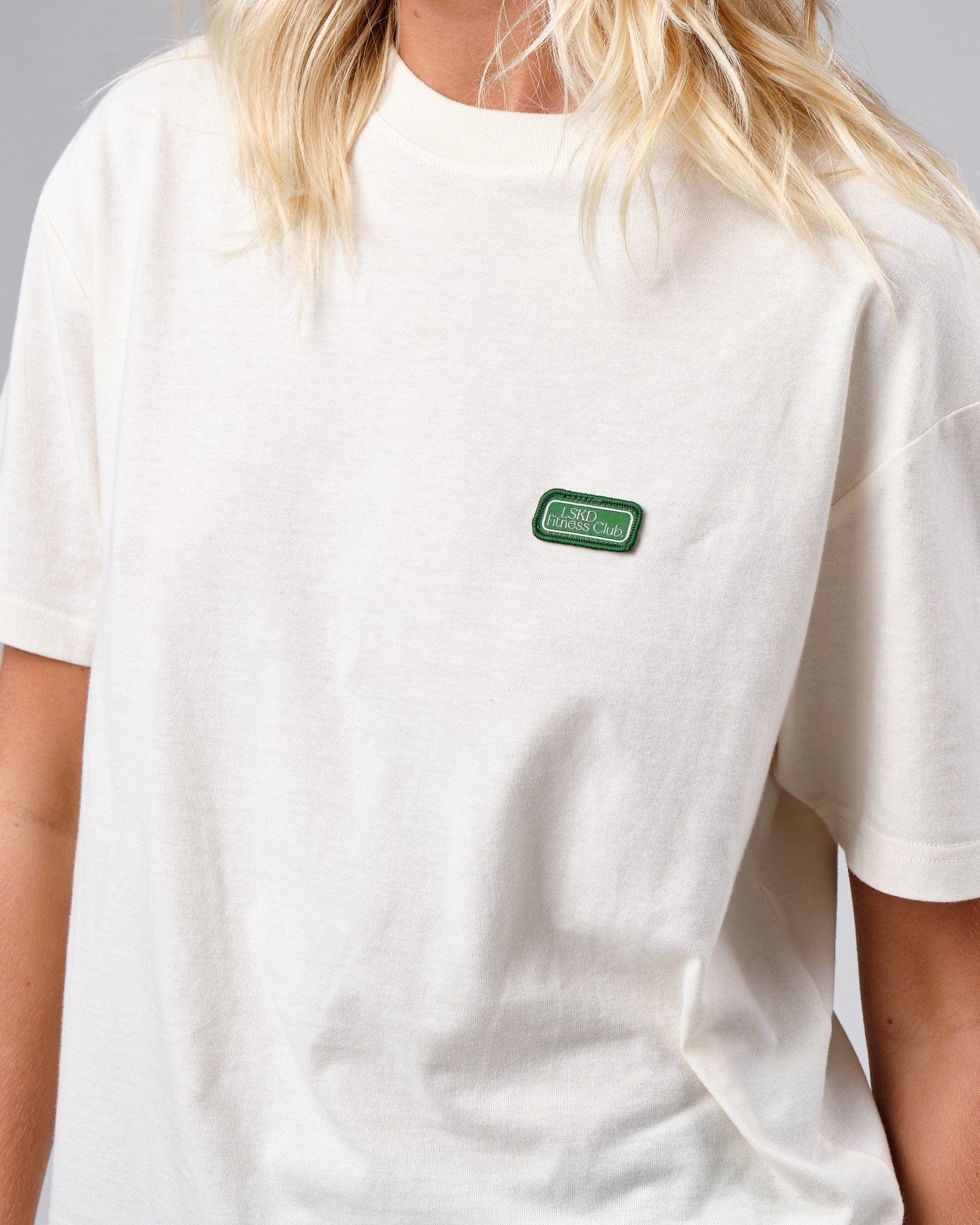 Model wearing Unisex Badge Tee Oversize - Cream