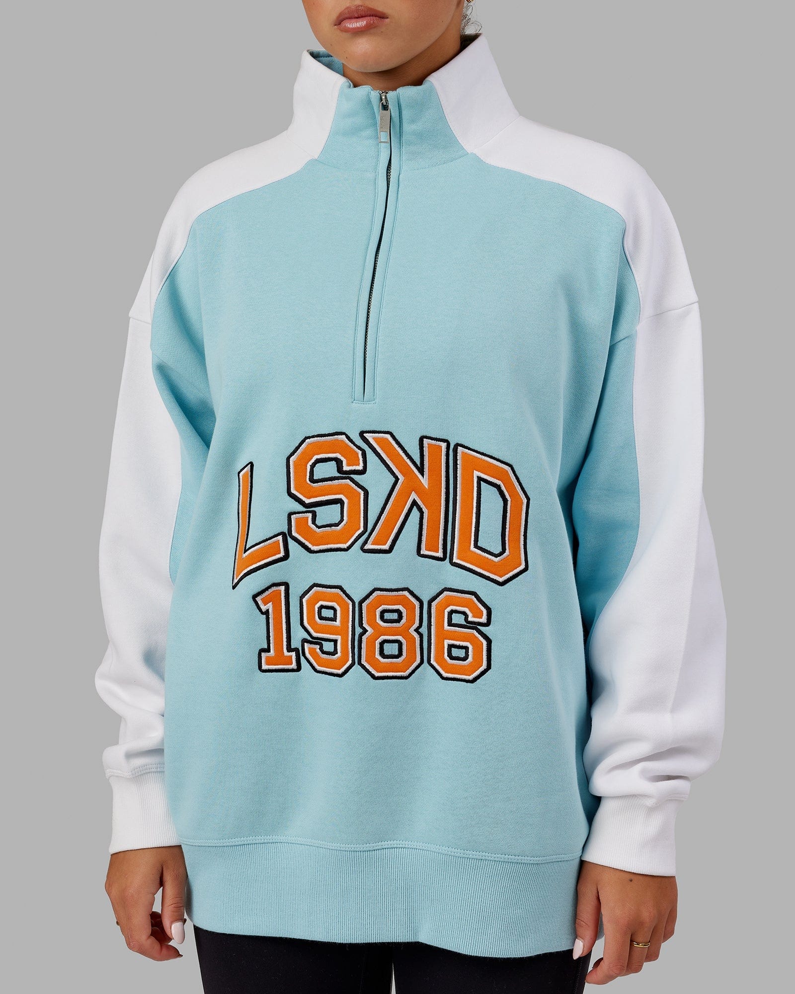 Model wearing Unisex Alumni 1/4 Zip Sweater Oversize - Crystal Blue-Orange Peel